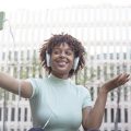 Young afro-haired student sitting on the campus stairs on a video call with her relatives
